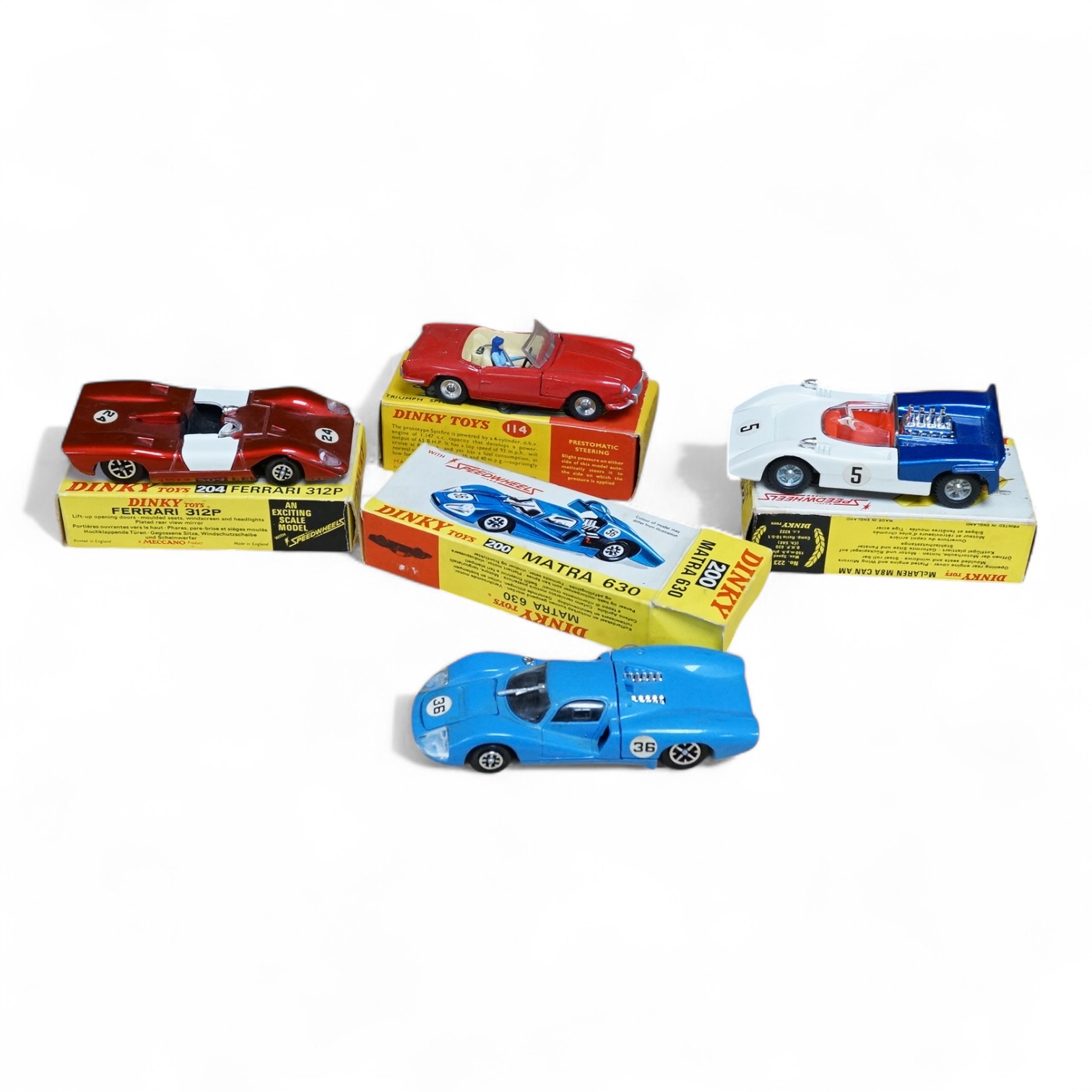 Four boxed Dinky Toys cars; a Triumph Spitfire (114) in red with cream interior, together with three Speedwheels; a Matra 630 (200) in blue, a Ferrari 312P (204) in metallic red, and a McLaren M8A Can Am (223) in white a